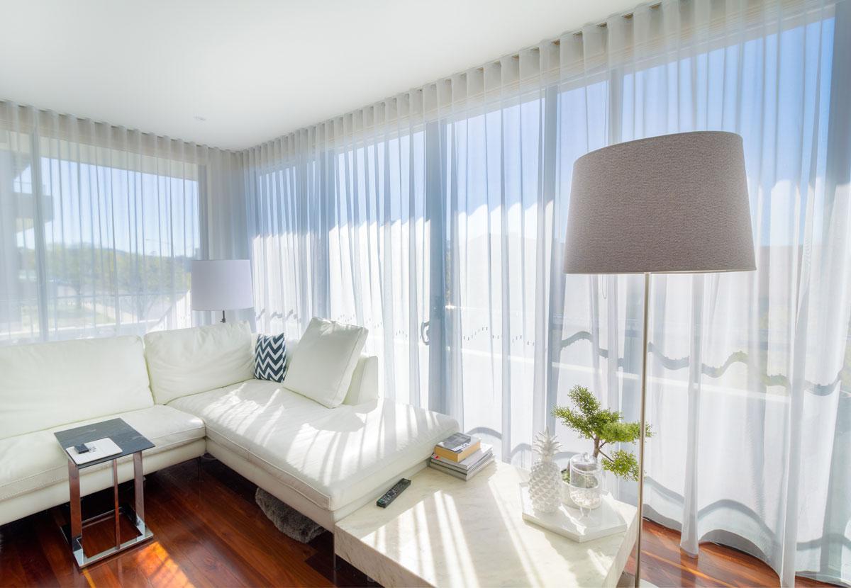 Bright white living room with sheer curtains, modern furniture, and natural daylight